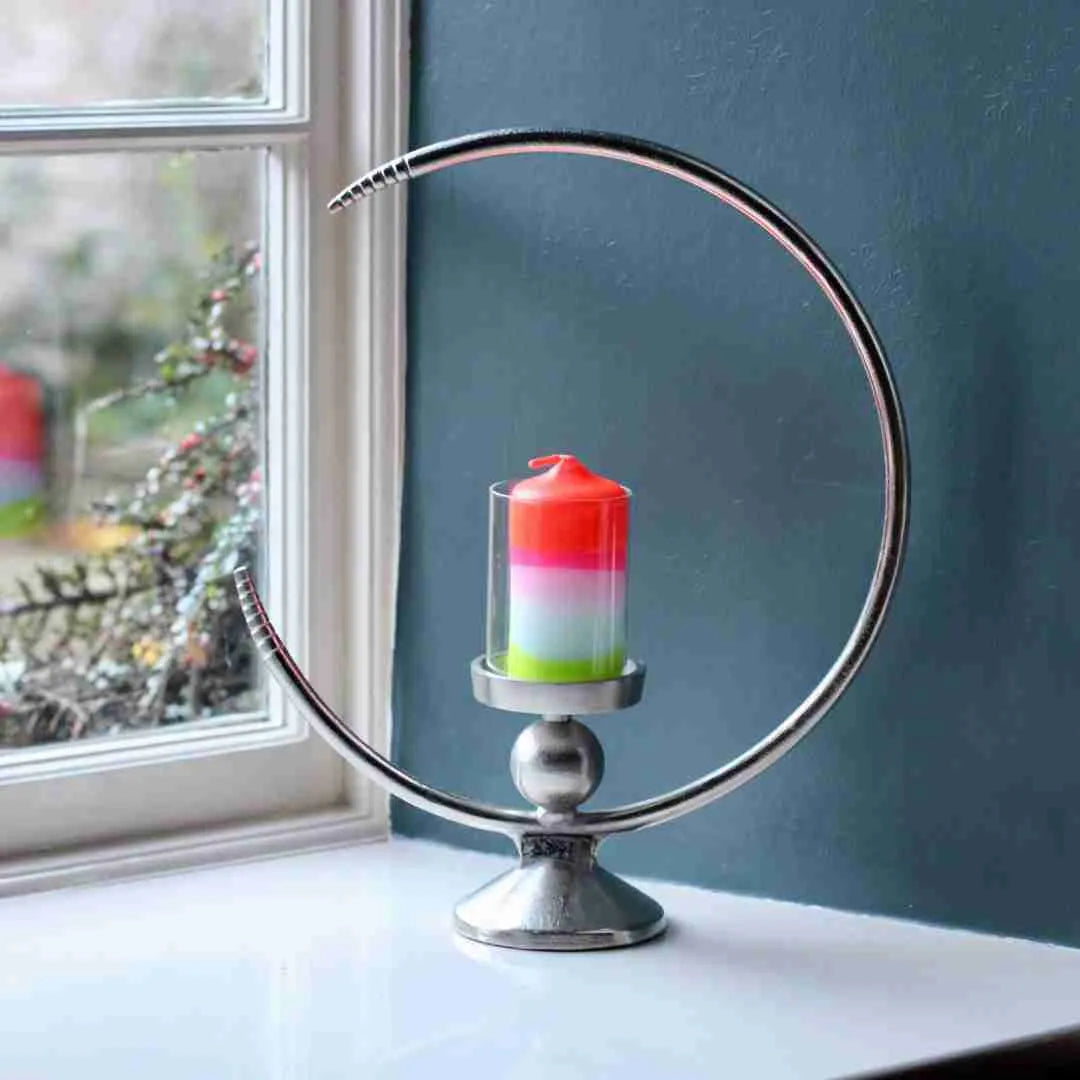 Half moon candle holder with a pink and green dip-dyed candle on a windowsill