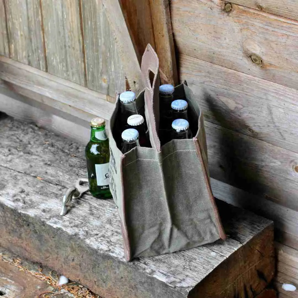 Canvas beer caddy with six bottles and a bottle opener on a bench