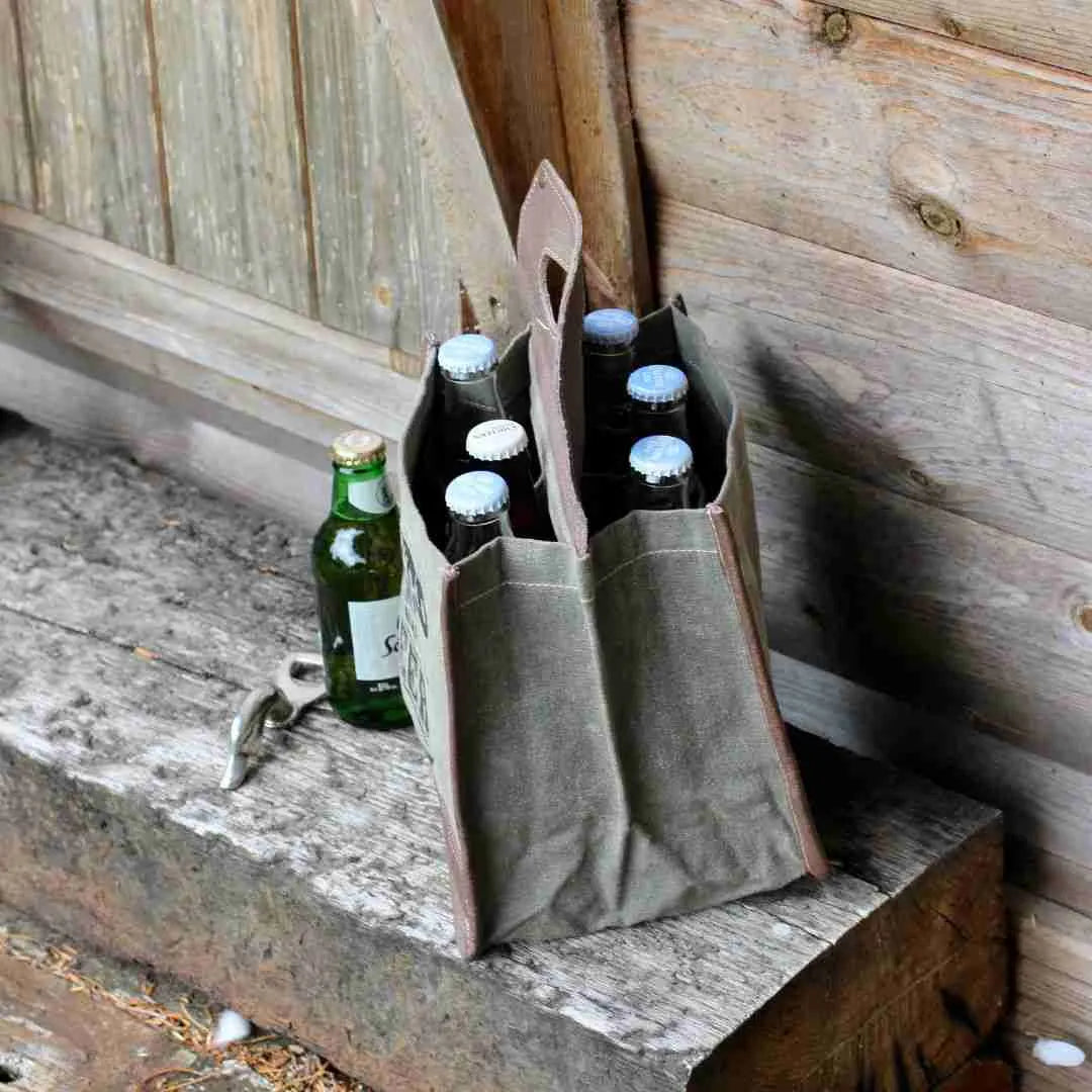 Canvas beer caddy with six bottles and a bottle opener on a bench