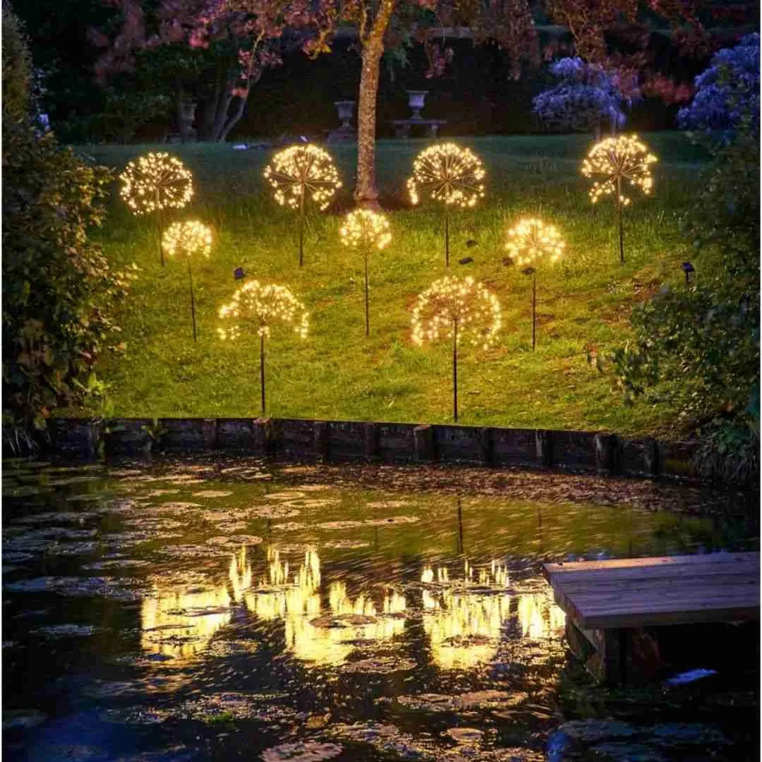 Dandelion starburst solar lights glowing around a garden pond at night