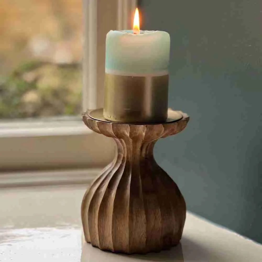 Close-up of the ribbed wooden candle holder holding a lit pillar candle