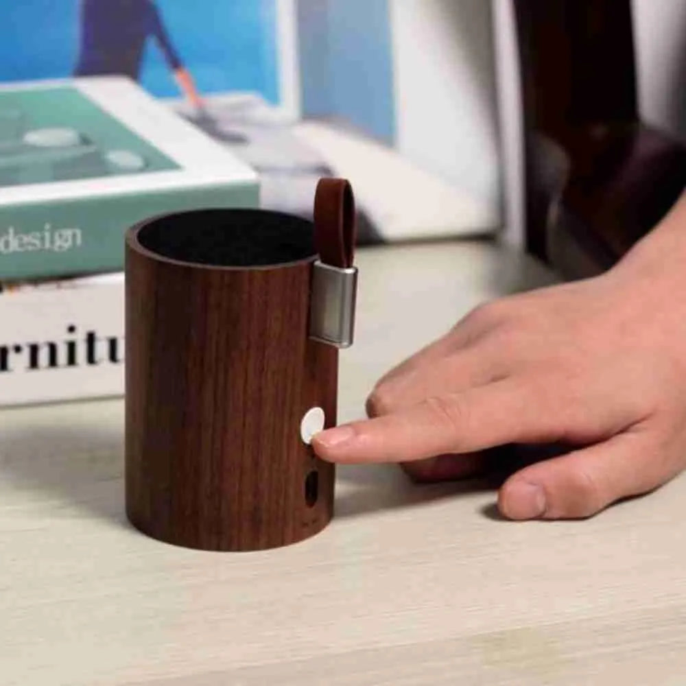 Hand touching the button on the walnut drum light speaker
