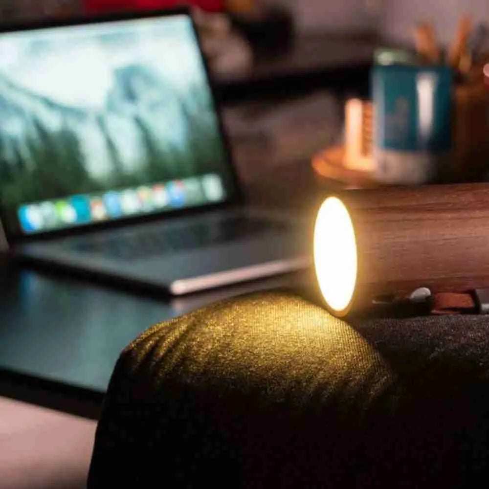 Drum light speaker lit up next to a laptop