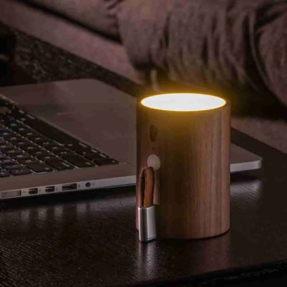 Drum light speaker glowing warm white beside a laptop