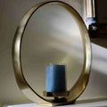 Brass circular candle holder with a blue pillar candle in a glass sleeve
