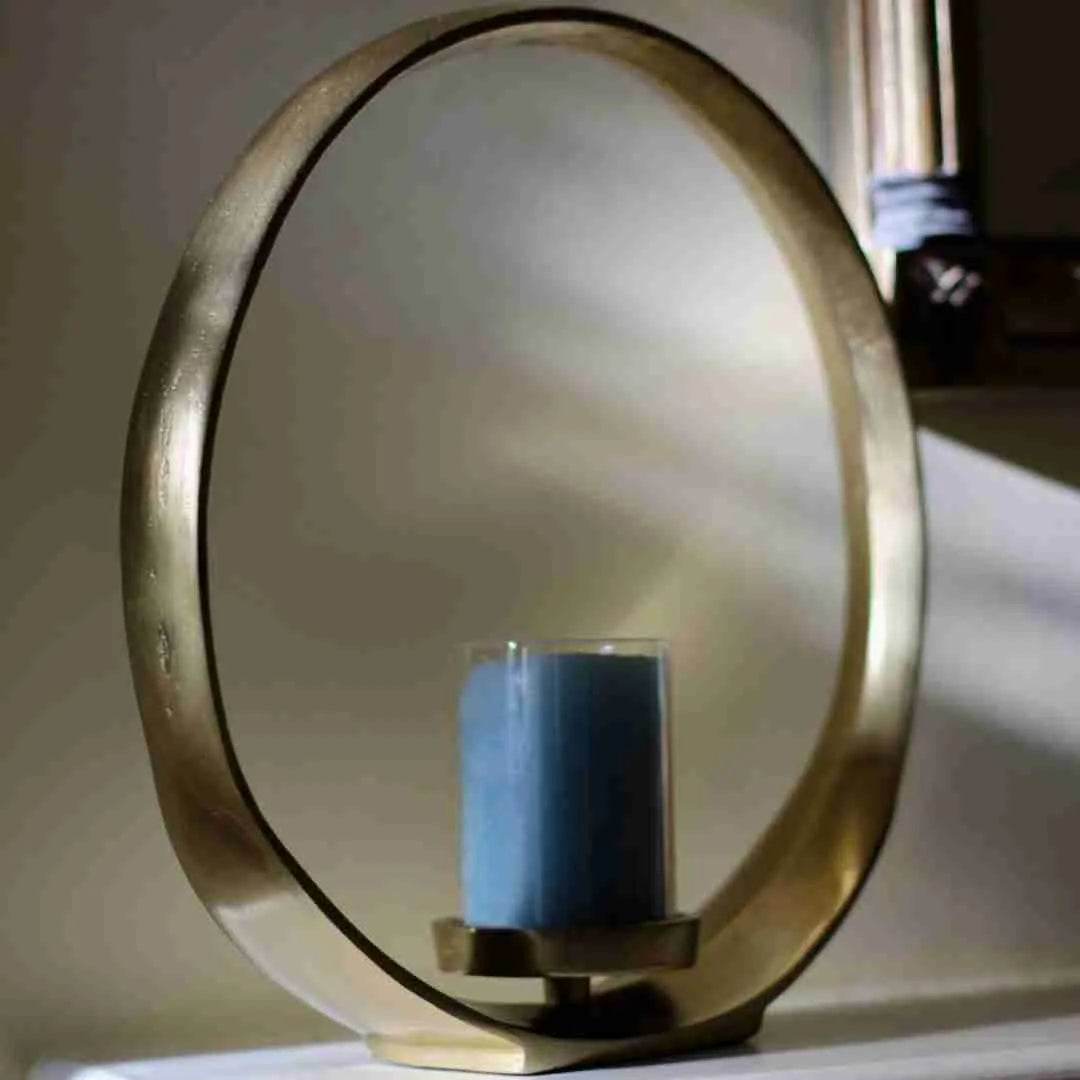 Brass circular candle holder with a blue pillar candle in a glass sleeve