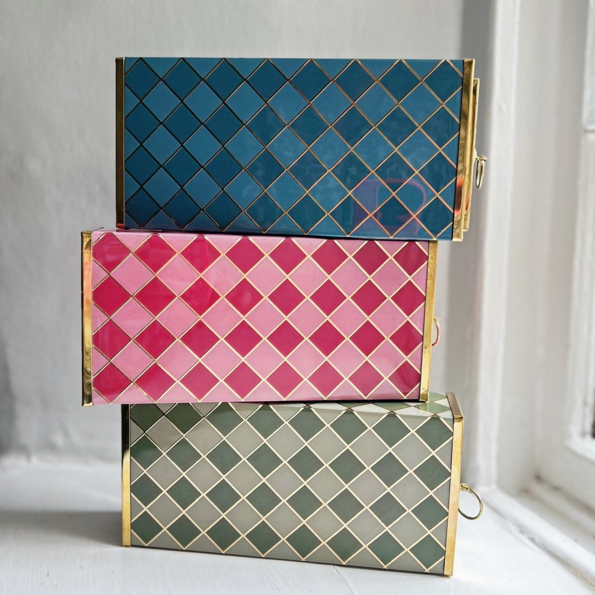 Harlequin matchboxes stacked in Denim Blue, Raspberry Pink and Sage Green