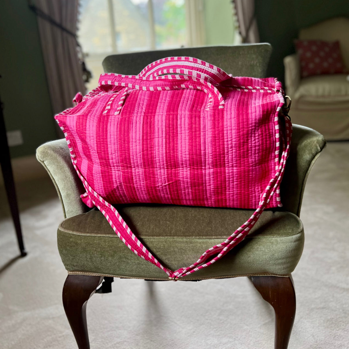 Harlequin quilted cotton weekend bag in fuchsia and magenta stripes on a chair