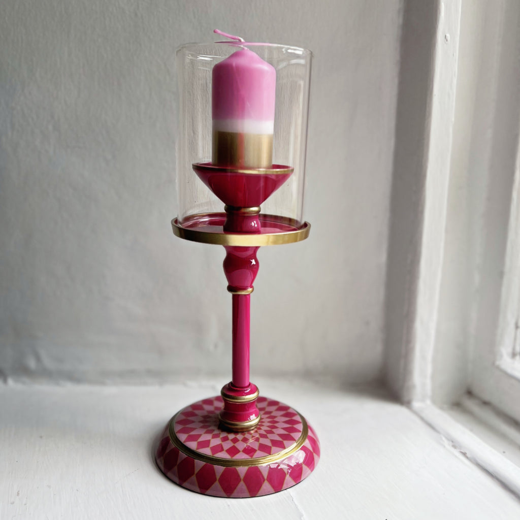 Small gold dipped pillar candle in pink, shown in a pink enamel candlestick
