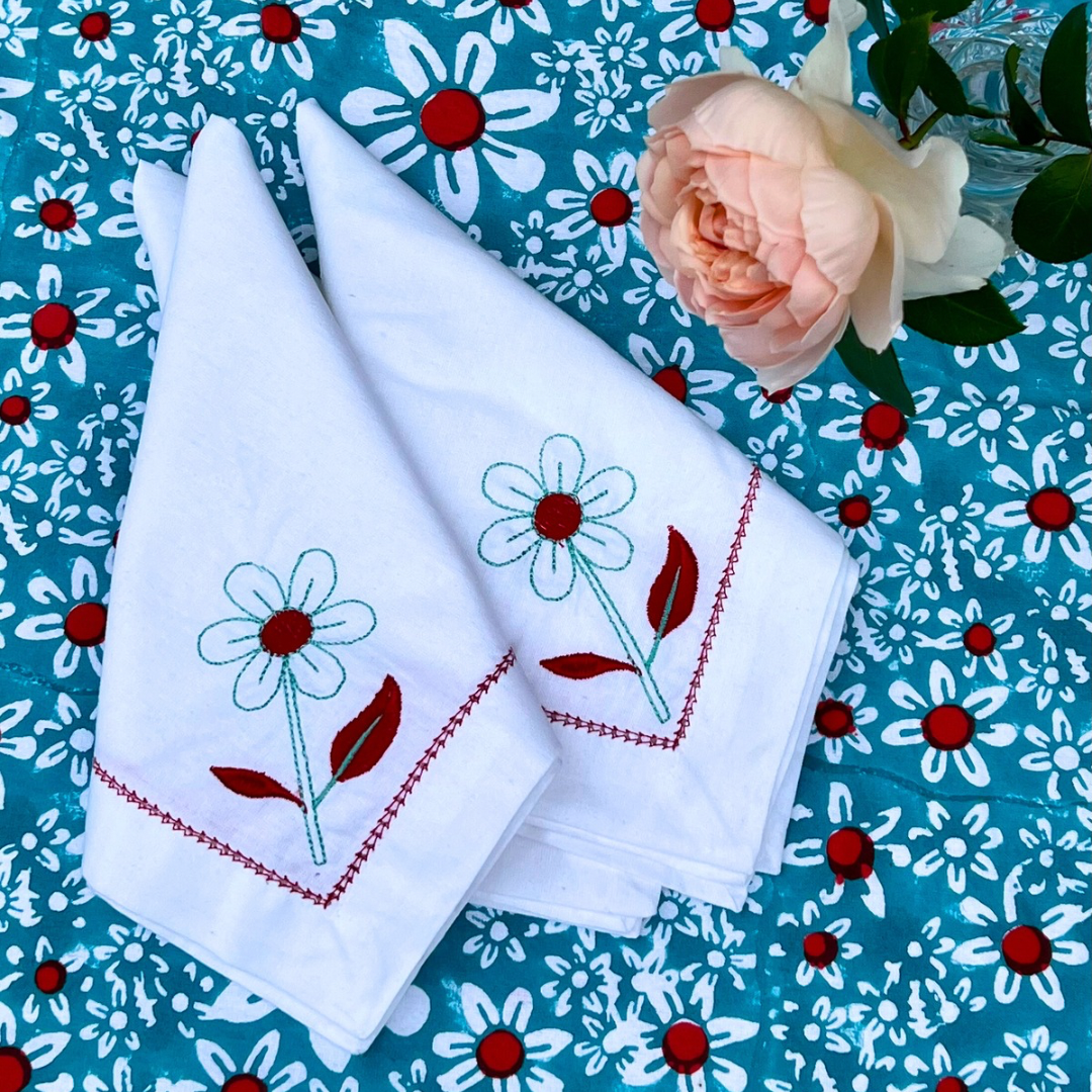 White cotton napkins with coral daisy embroidery