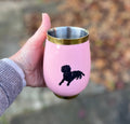 Pink insulated wine tumbler with a black dog design, held in a hand