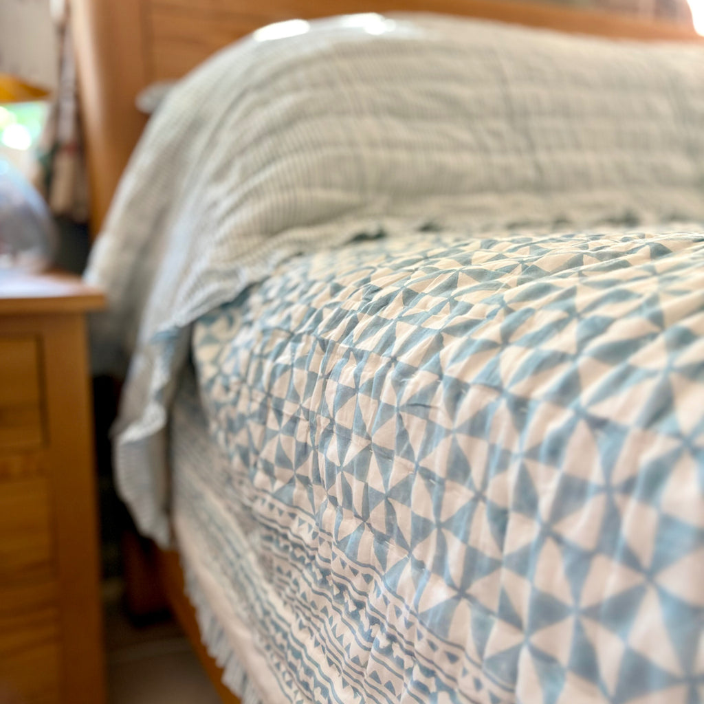 Harlequin reversible cotton quilt in Sea Breeze Blue on a double bed