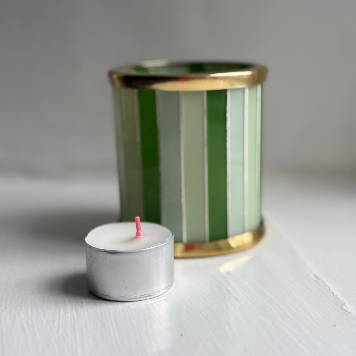 Bolsius tealight candle beside a green striped glass tealight holder