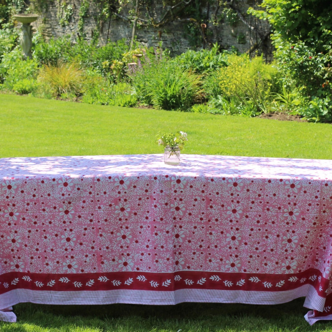 Pink daisies tablecloth with a deep red border on a garden table