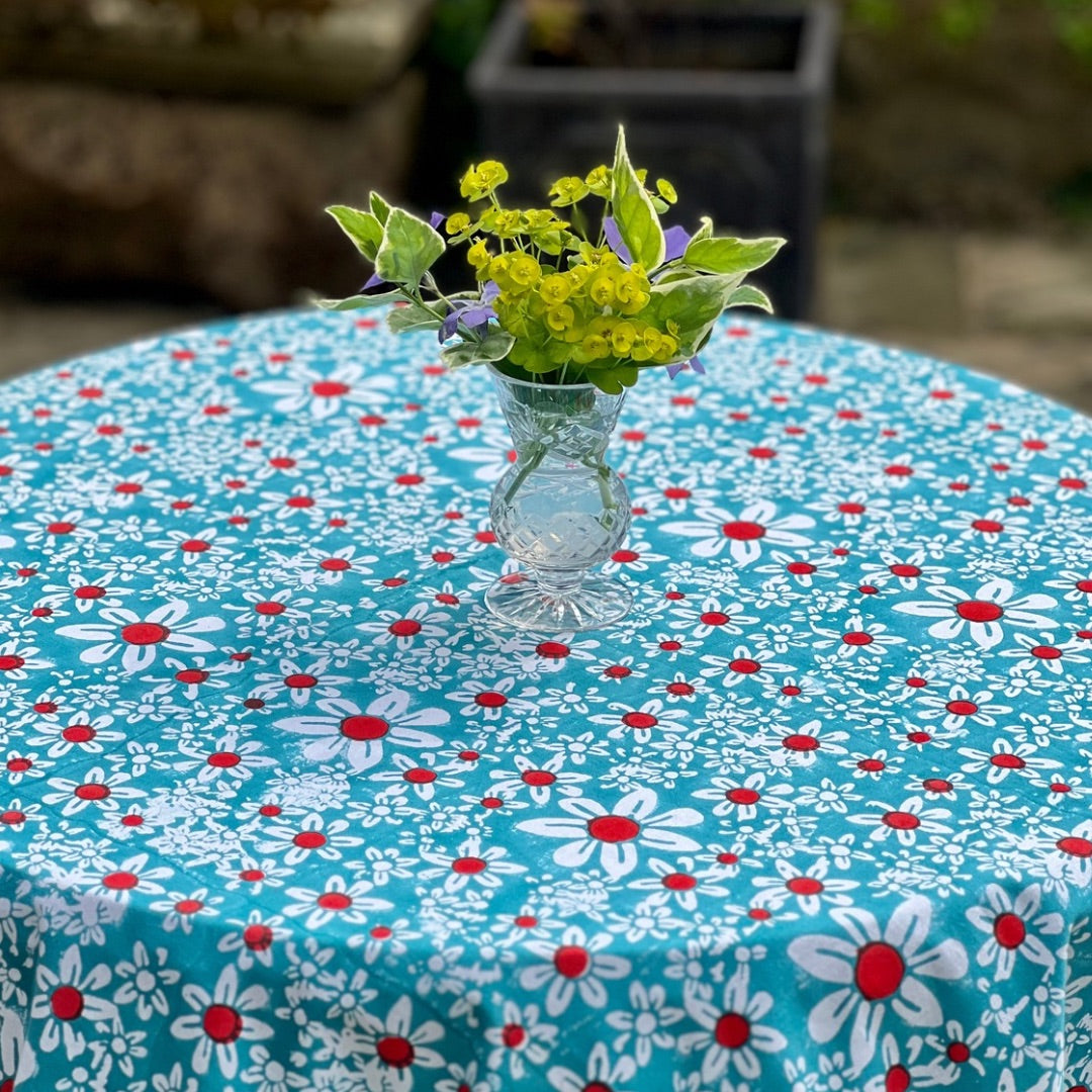 Turquoise tablecloth printed with white and red daisies