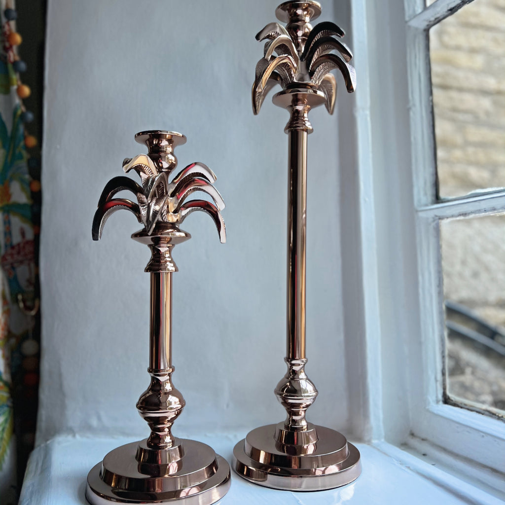 Small and large palm tree candlesticks in rose gold side by side