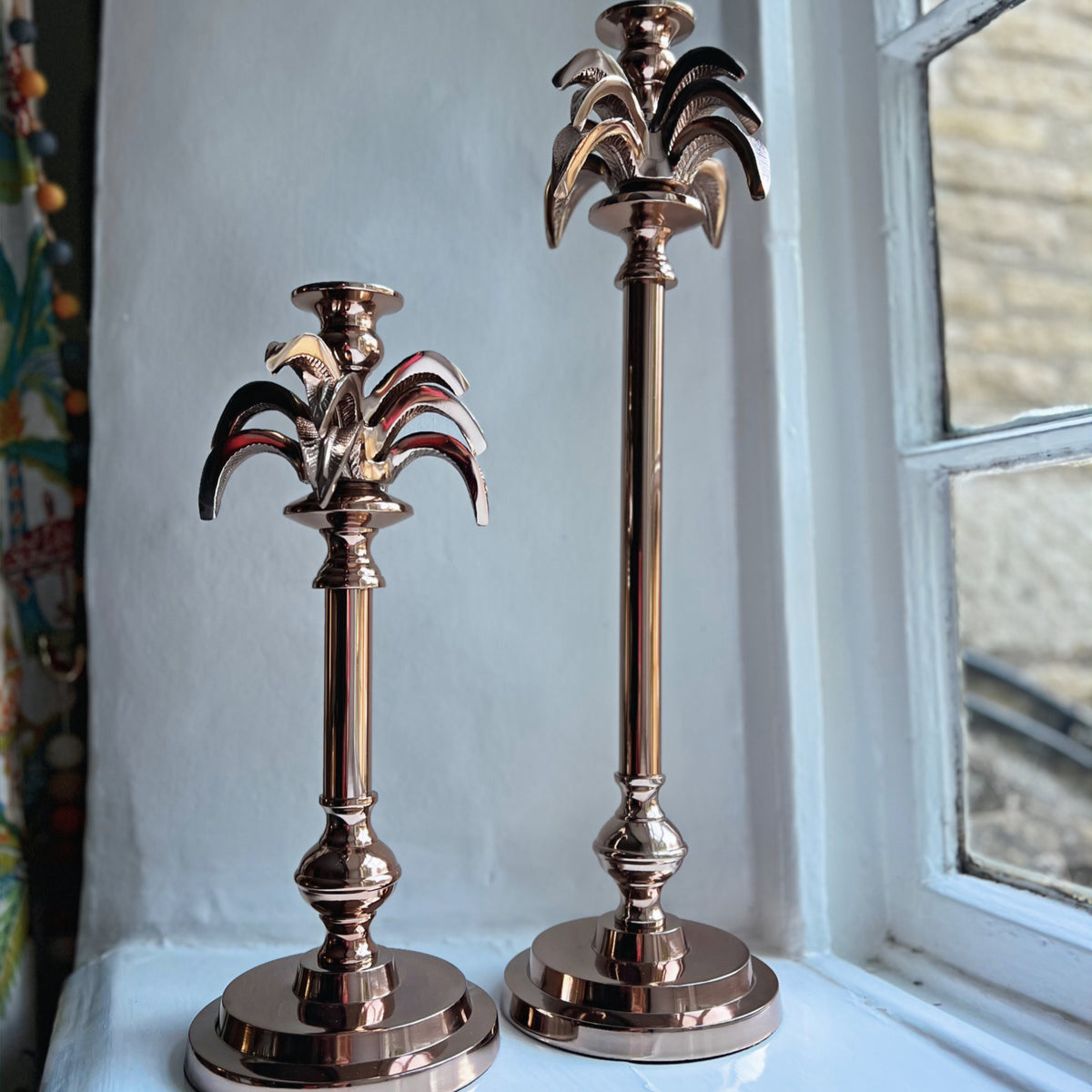 Small and large palm tree candlesticks in rose gold side by side