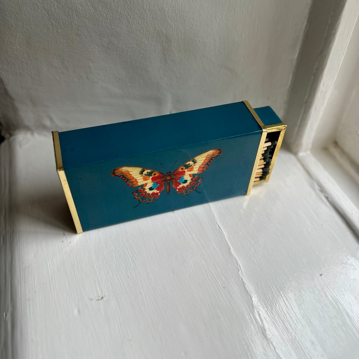 Butterfly oversized matchbox in teal enamel and brass, angled view