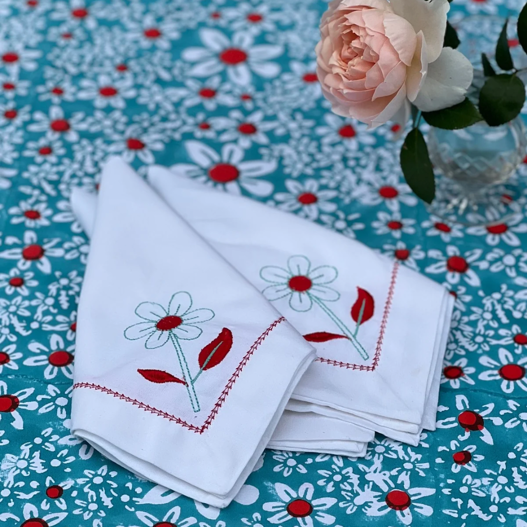 Coral daisy embroidered cotton napkins on a turquoise daisies tablecloth