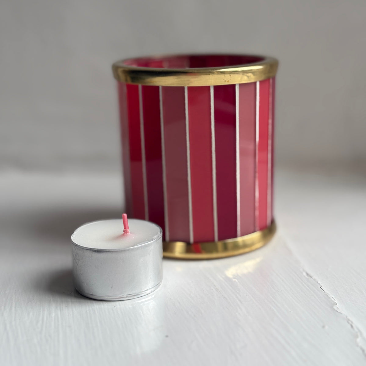 Bolsius tealight candle beside a pink striped glass tealight holder