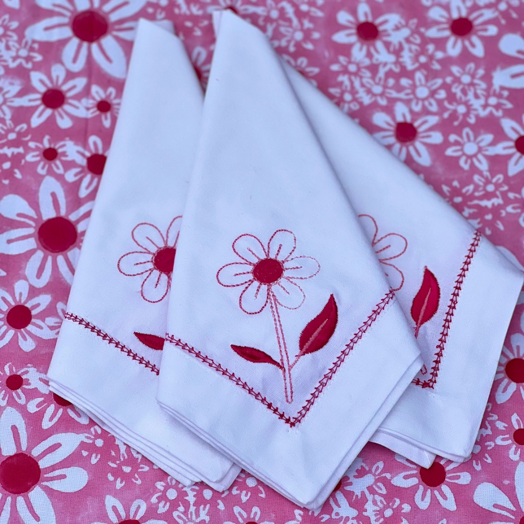 Close-up of white cotton napkins with pink daisy embroidery