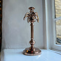 Small palm tree candlestick in rose gold on a windowsill