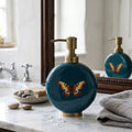 Butterfly enamel and brass soap dispenser in teal beside a bathroom basin