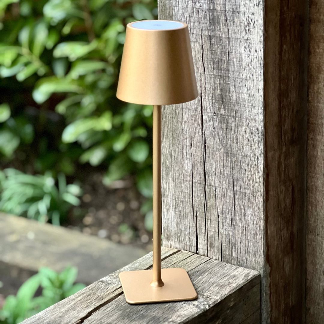 Gold LED cordless table lamp on a garden table