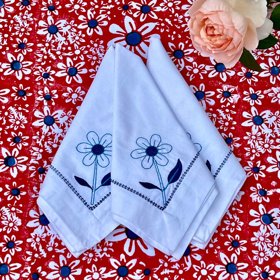White cotton napkins with blue daisy embroidery and edging