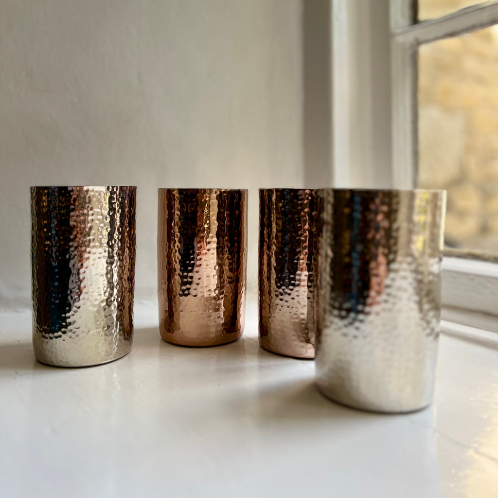 Row of hammered metal tumblers in silver and rose gold