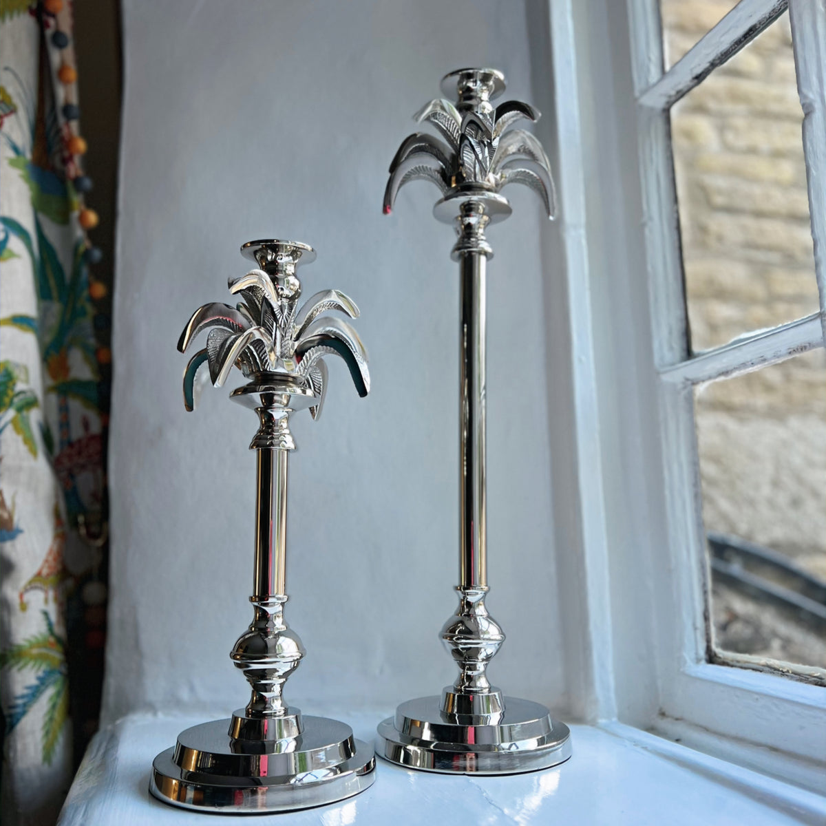 Large and small palm tree candlesticks in silver side by side