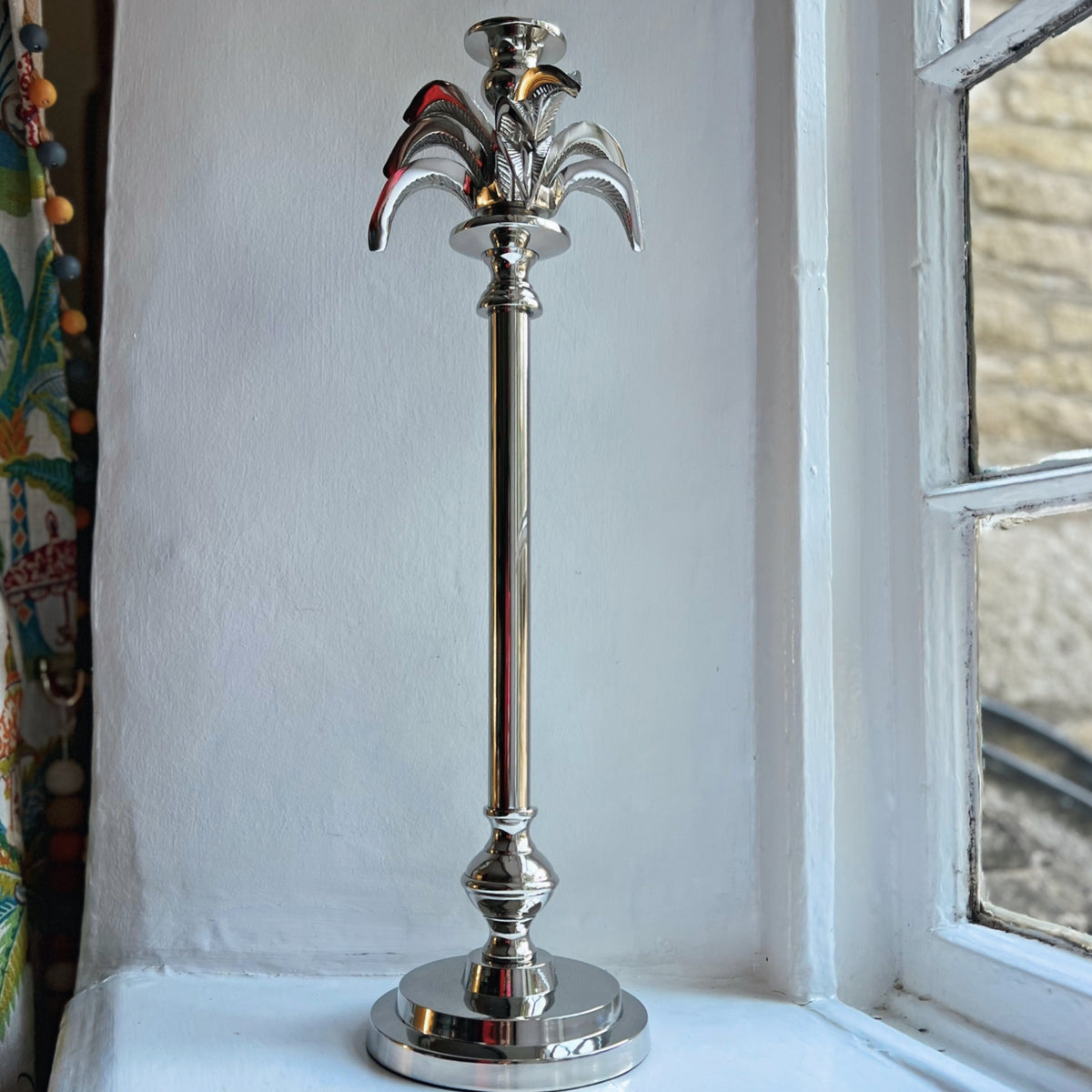 Large palm tree candlestick in silver on a windowsill