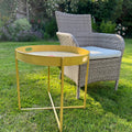 Gold folding tray stand with a round tray, on a garden lawn