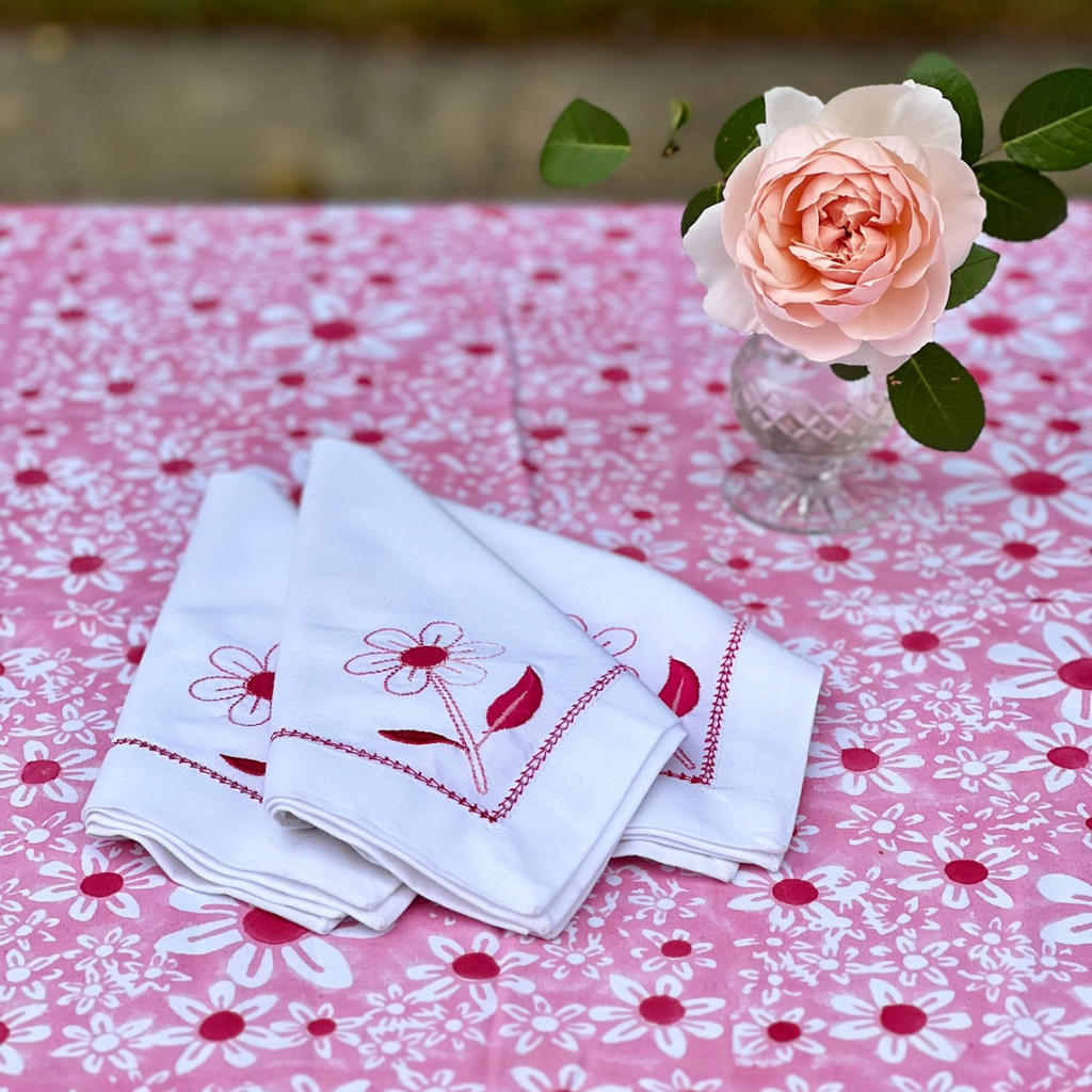 Pink daisy embroidered cotton napkins on a pink floral tablecloth