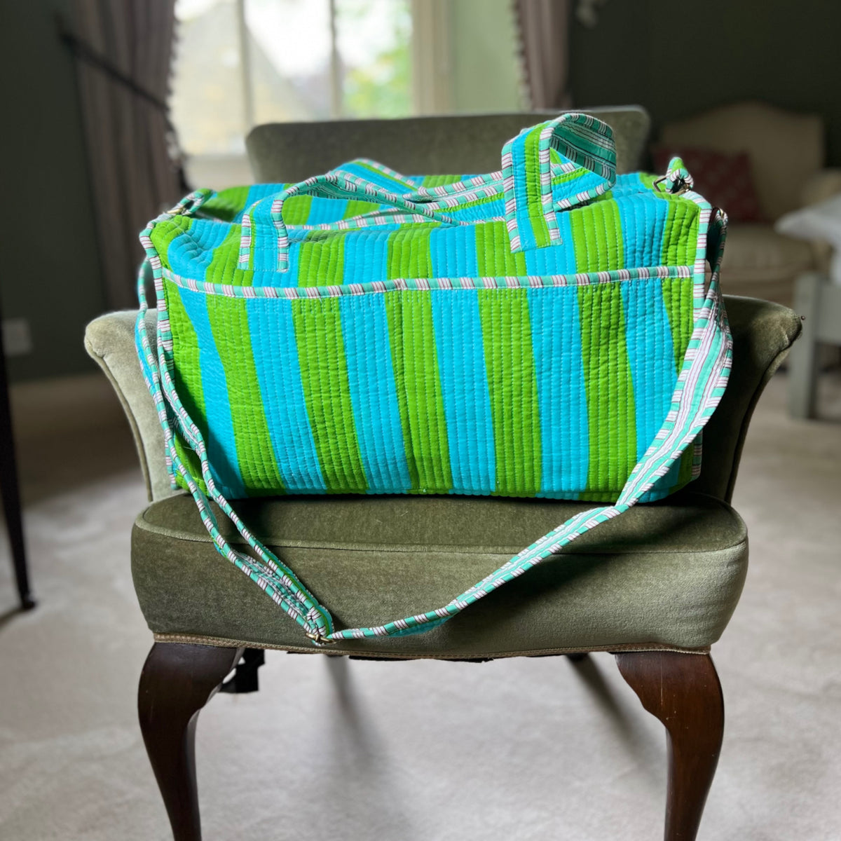 Harlequin quilted cotton weekend bag in lime and blue stripes on a chair