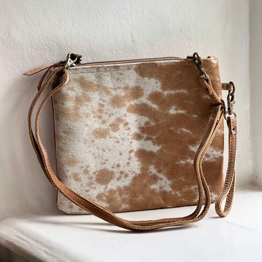 Square crossbody bag in tan and white cowhide with a long leather strap