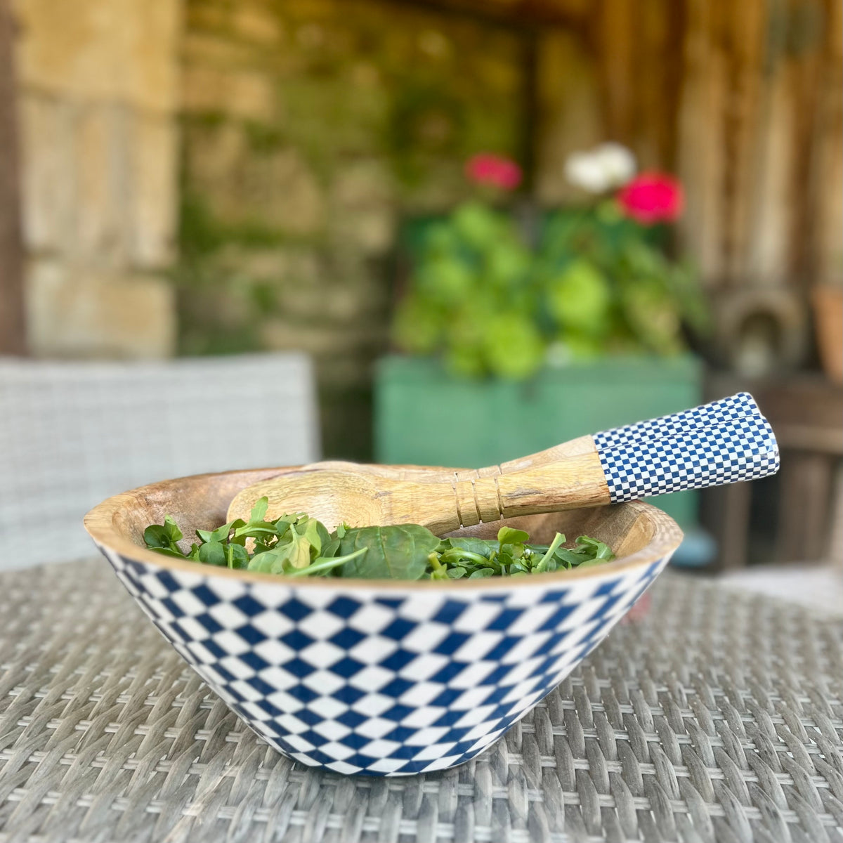 Checked enamel bowl of salad with matching wooden salad servers