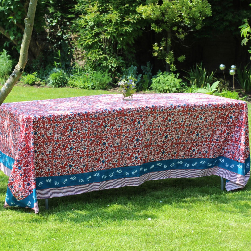 Red daisies tablecloth on a long table in a garden