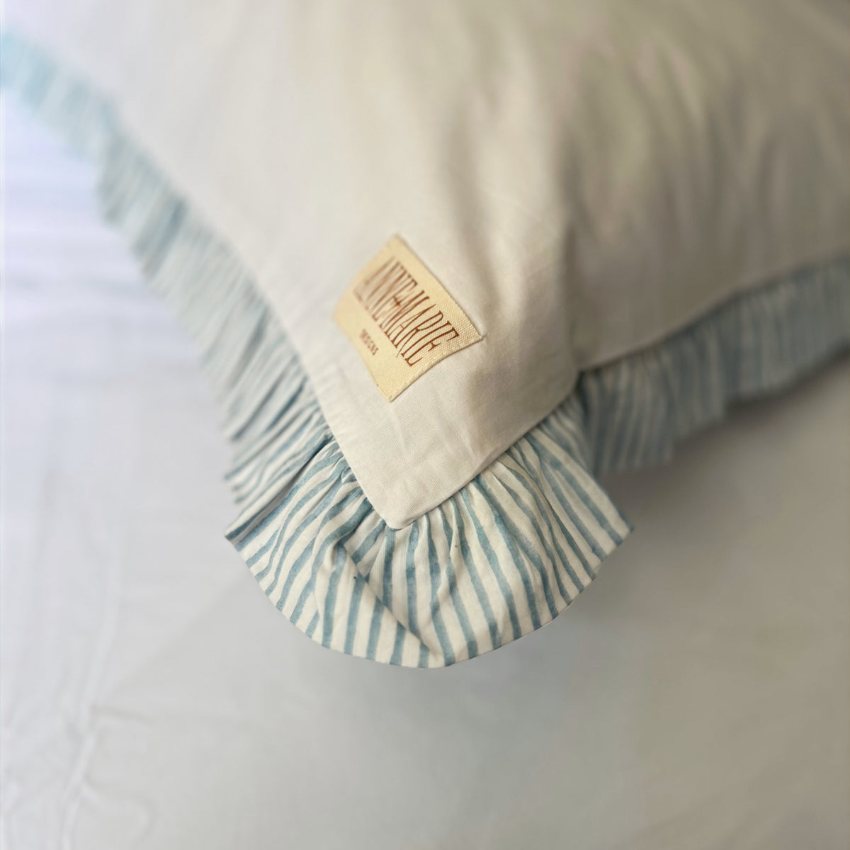 Corner of a Sea Breeze Blue Harlequin pillowcase showing the label and frill