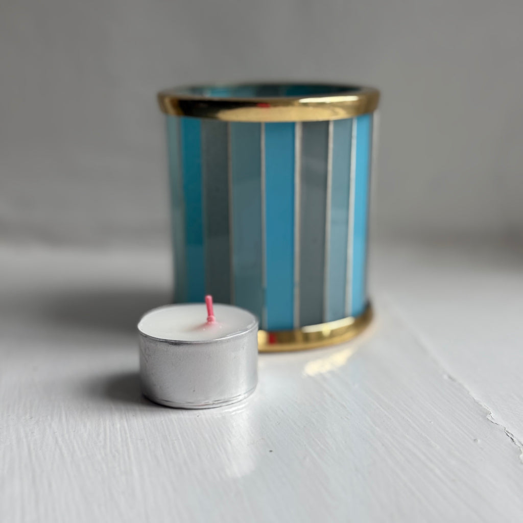 Bolsius tealight candle beside a blue striped glass tealight holder