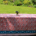 Red daisies rectangular tablecloth with a blue border on a garden table