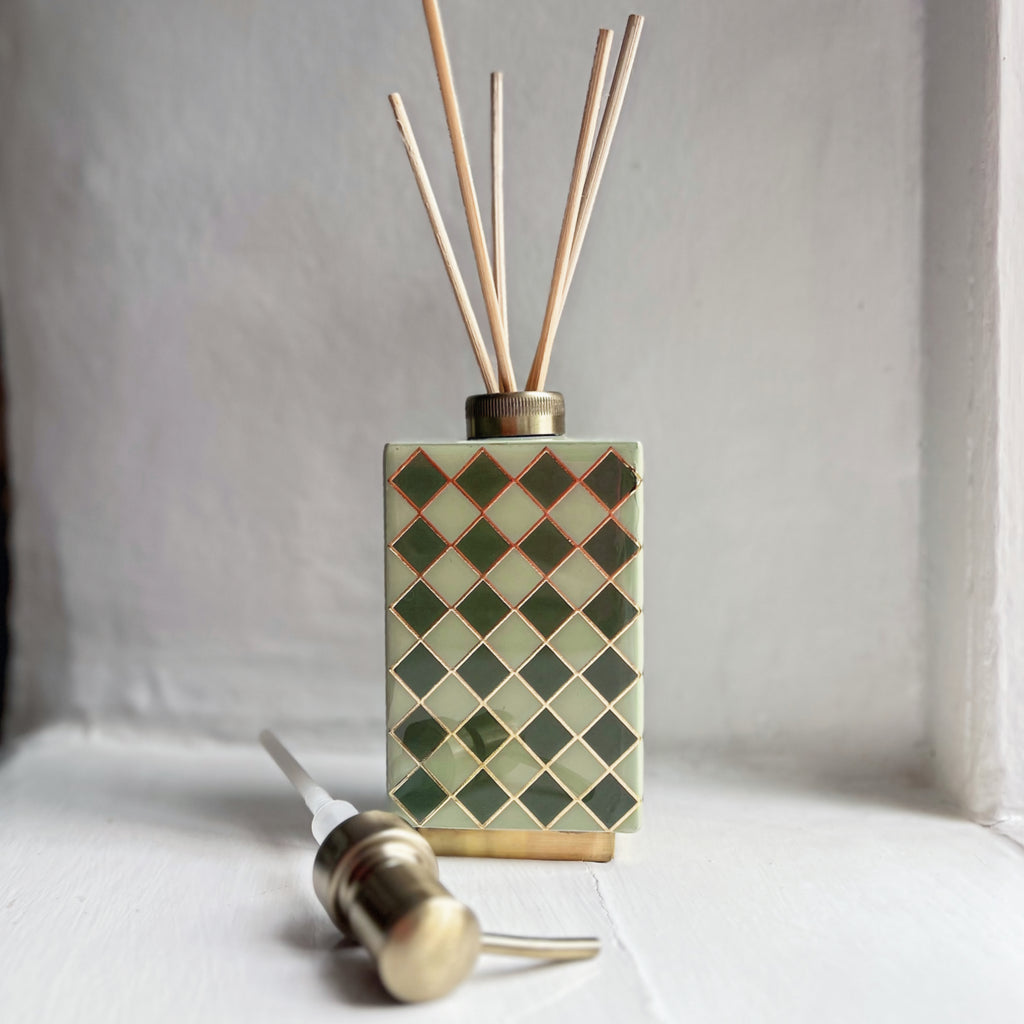 Harlequin enamel and brass multi-use bottle in Sage Green used as a reed diffuser
