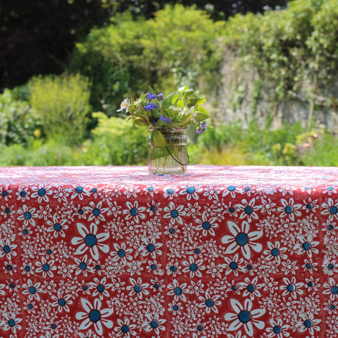 Close-up of the red daisies block print tablecloth with a vase of flowers