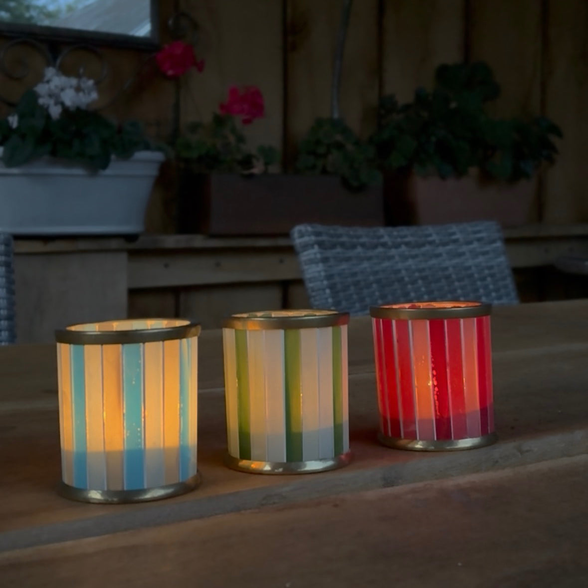 Striped glass tealight holders lit with candles in three colours