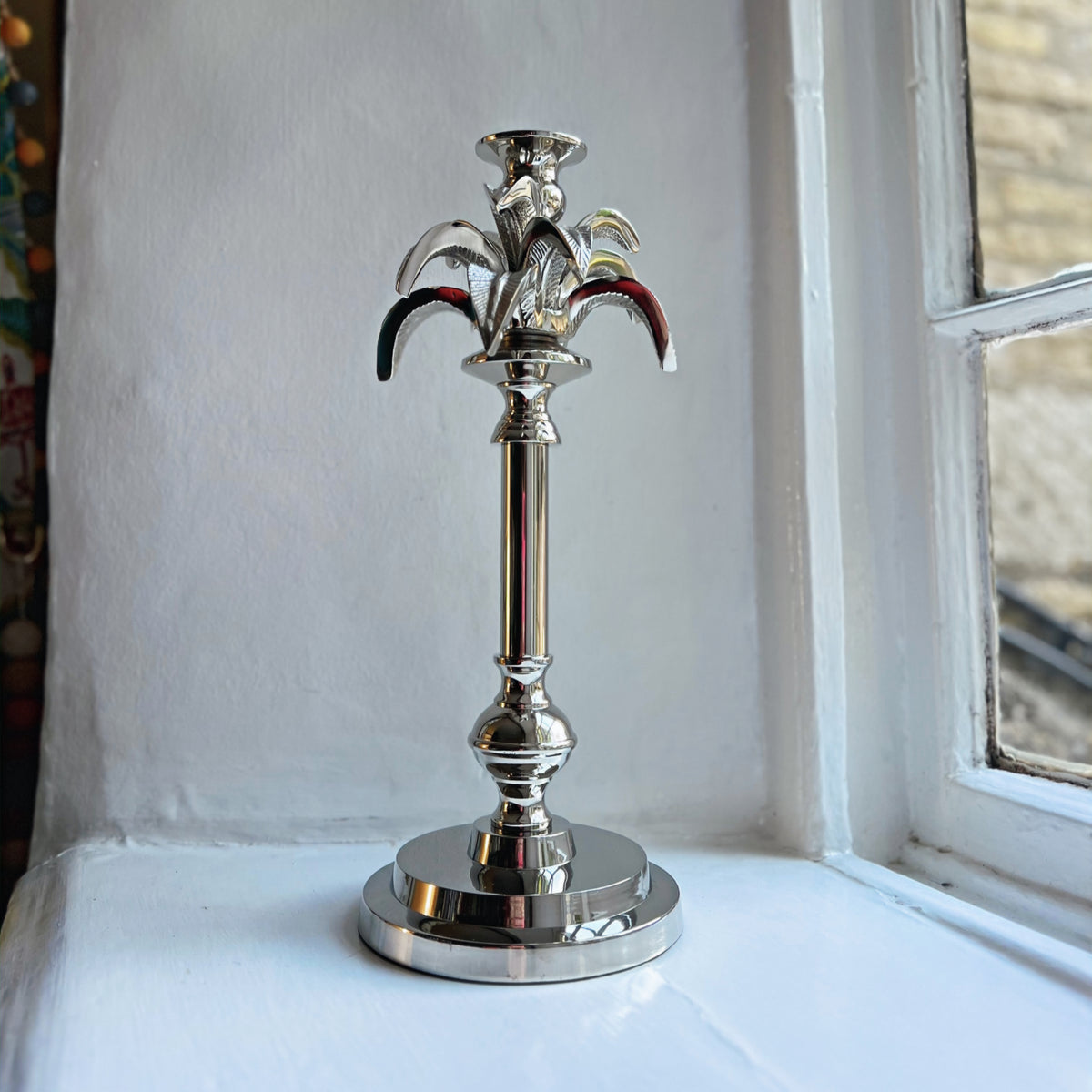 Small palm tree candlestick in silver on a windowsill