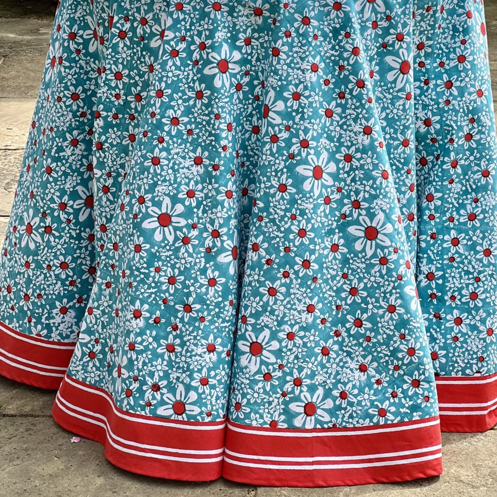 Close-up of the red and white striped hem on the turquoise daisies tablecloth
