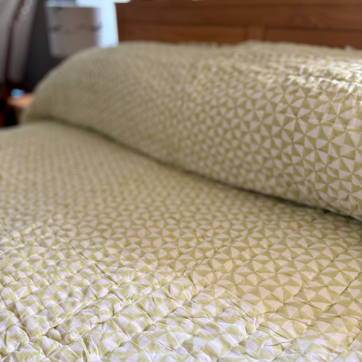 Harlequin reversible cotton quilt in Apple Green on a double bed