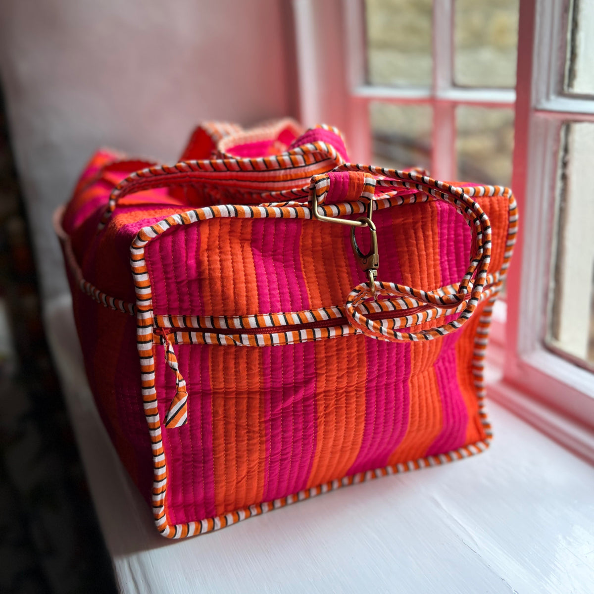 Harlequin quilted cotton weekend bag in orange and pink stripes with its shoulder strap